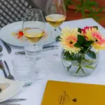 Tavolo elegante all'aperto con vino e fiori