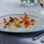 Piatto gourmet con decorazioni floreali.